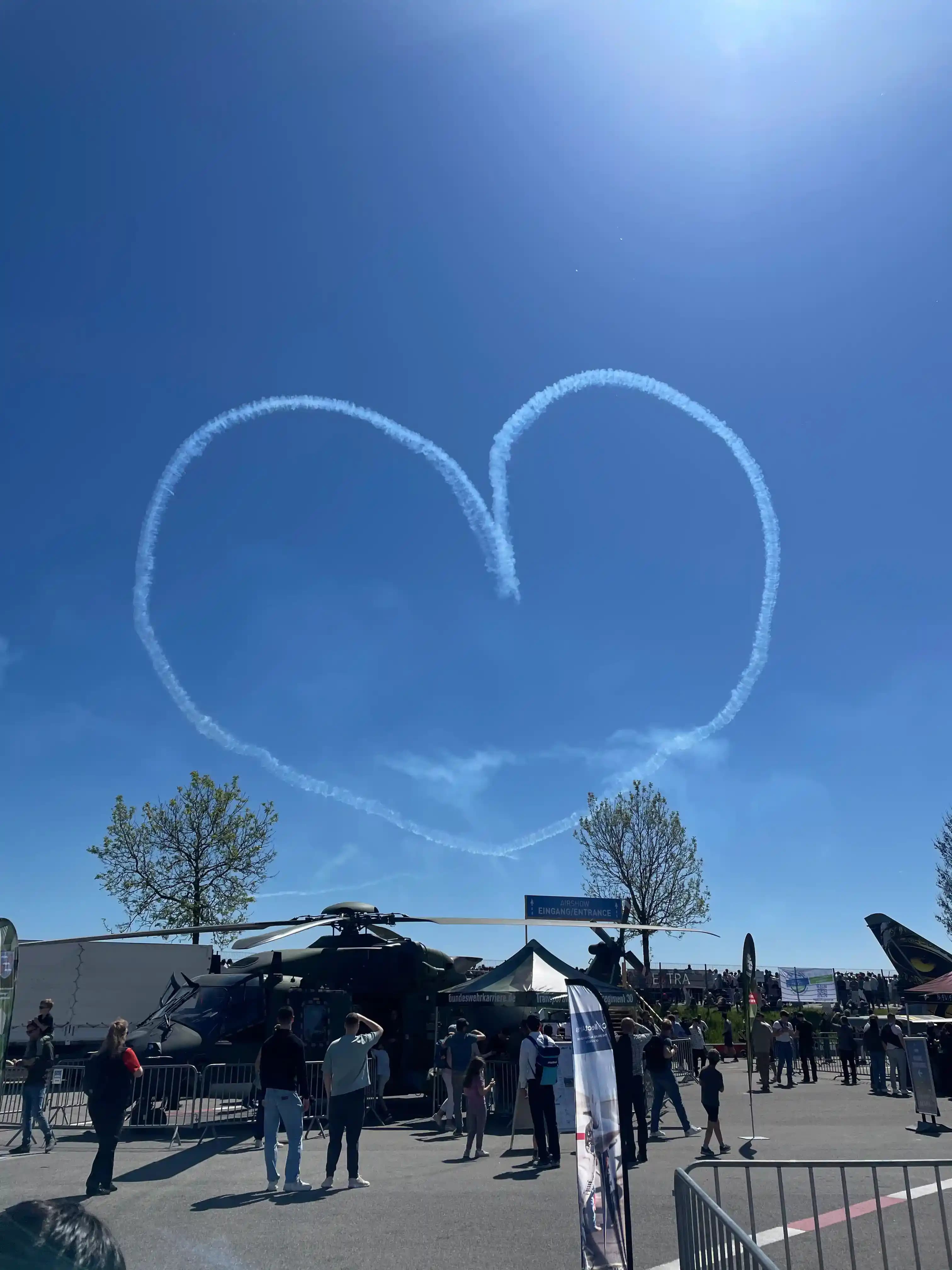 Heart-shaped skywriting above AERO Friedrichshafen airshow with exhibition aircraft on the ground