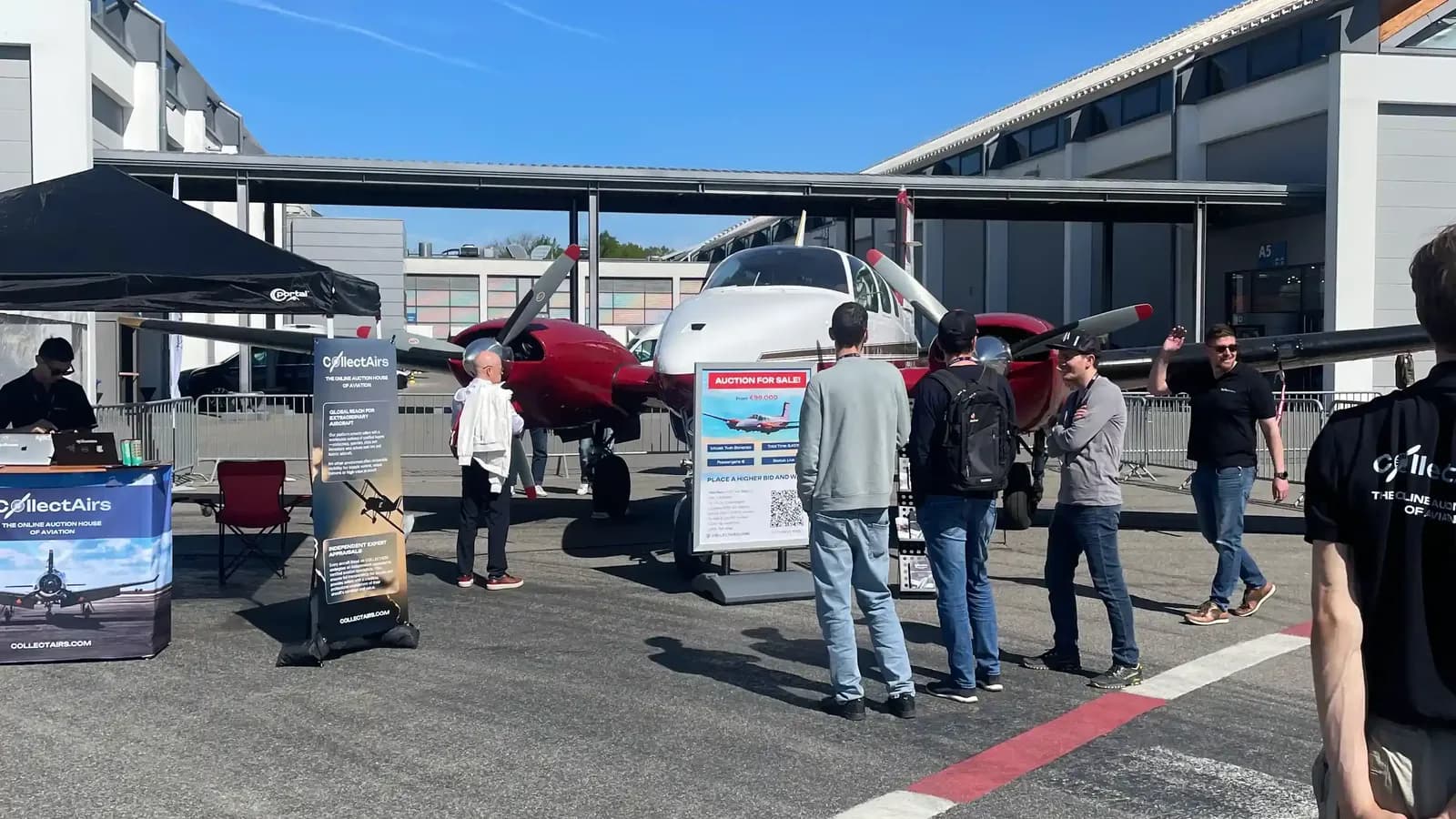 CollectAirs booth with Beechcraft Twin Bonanza and live auction signage at AERO 2026