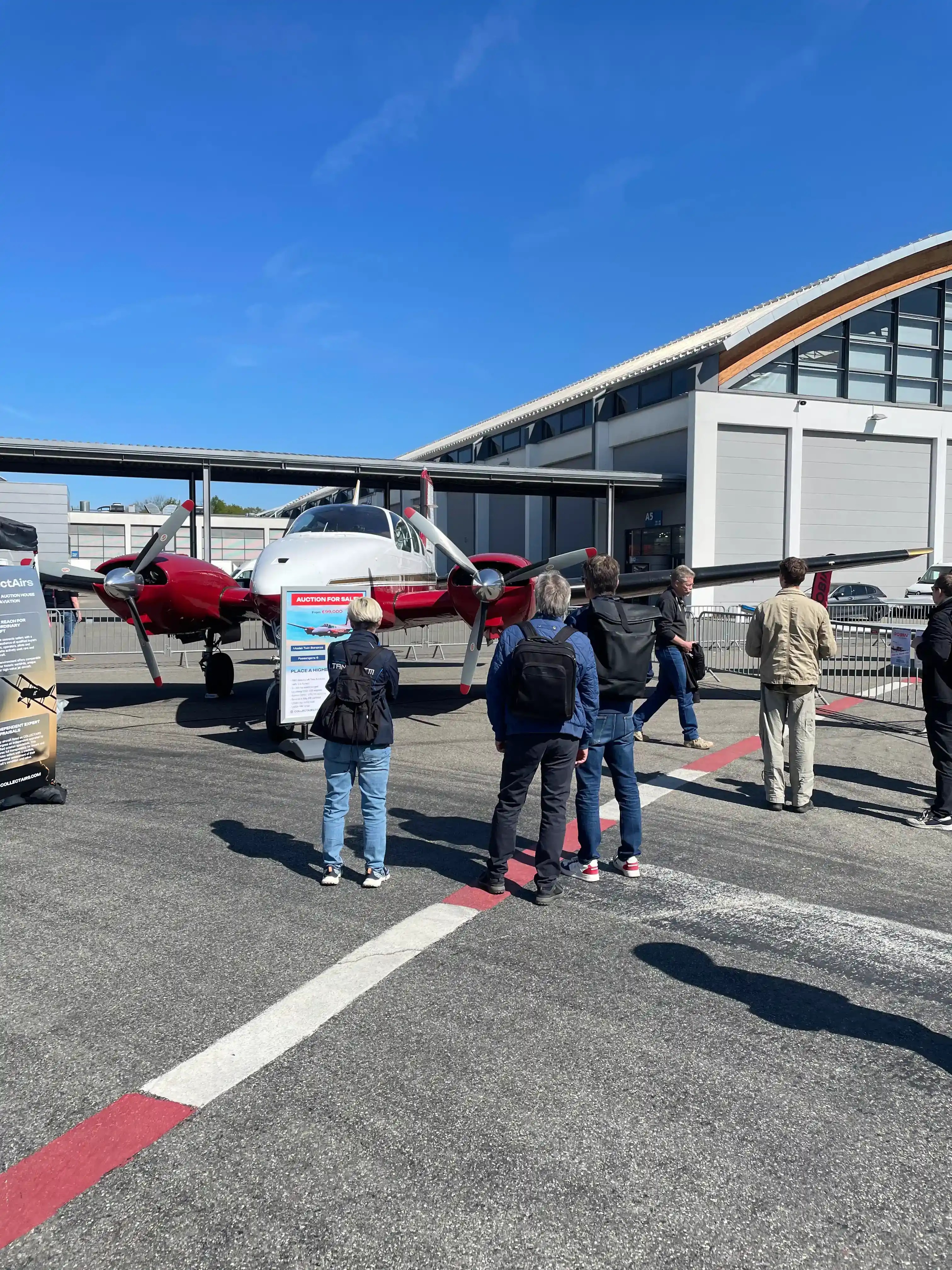 Visitors viewing Beechcraft Twin Bonanza aircraft auction display at AERO Friedrichshafen