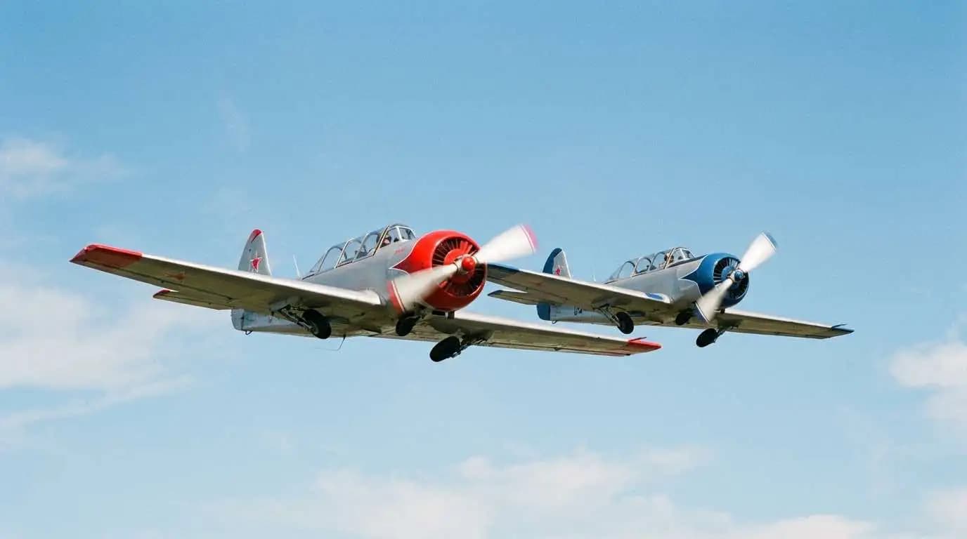 Two Yak 52 aircraft flying in close formation against a clear blue sky