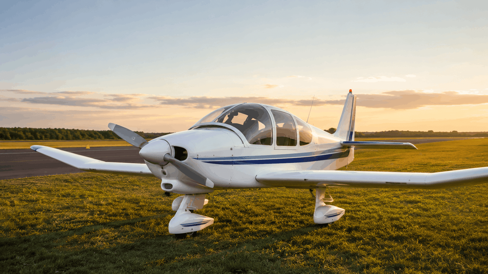 Classic French-style wooden four-seat aircraft on a misty grass airfield at sunrise