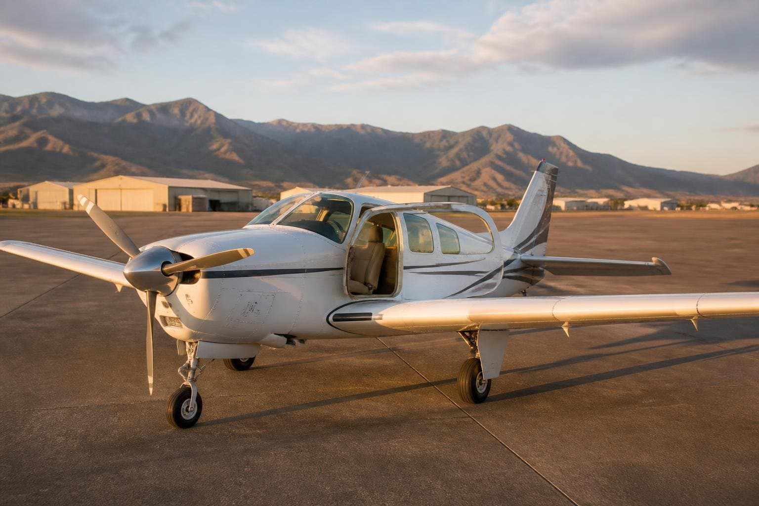 Generic late-1970s six-seat retractable piston aircraft on an airport apron at early morning