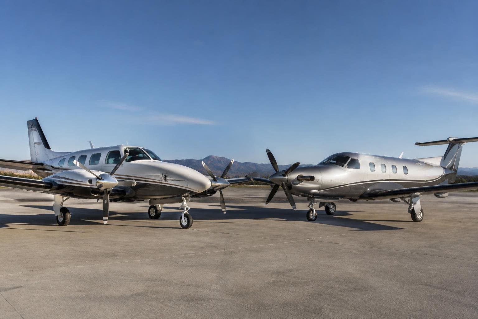 Pressurized piston aircraft and modern single-engine turboprop parked nose-to-nose on a sunlit airport apron