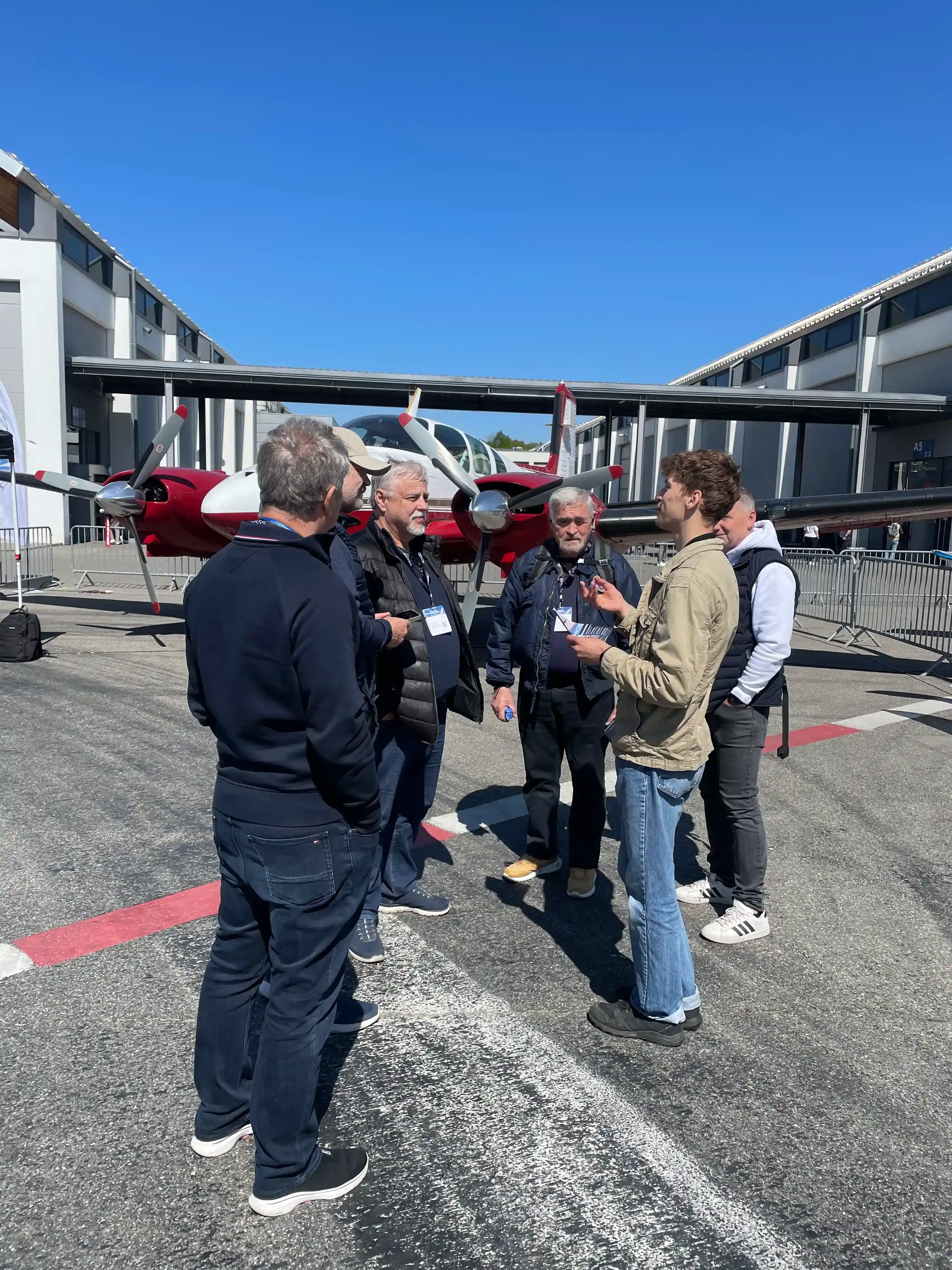 Aviation professionals networking beside twin-engine aircraft at AERO Friedrichshafen 2026